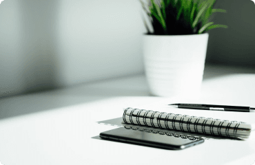 A clean workspace with notebook, pen, and phone on a desk.
