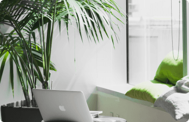 A laptop beside a bright window in a modern workspace.