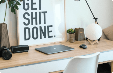 A tidy desk with a laptop and framed print in a modern office.