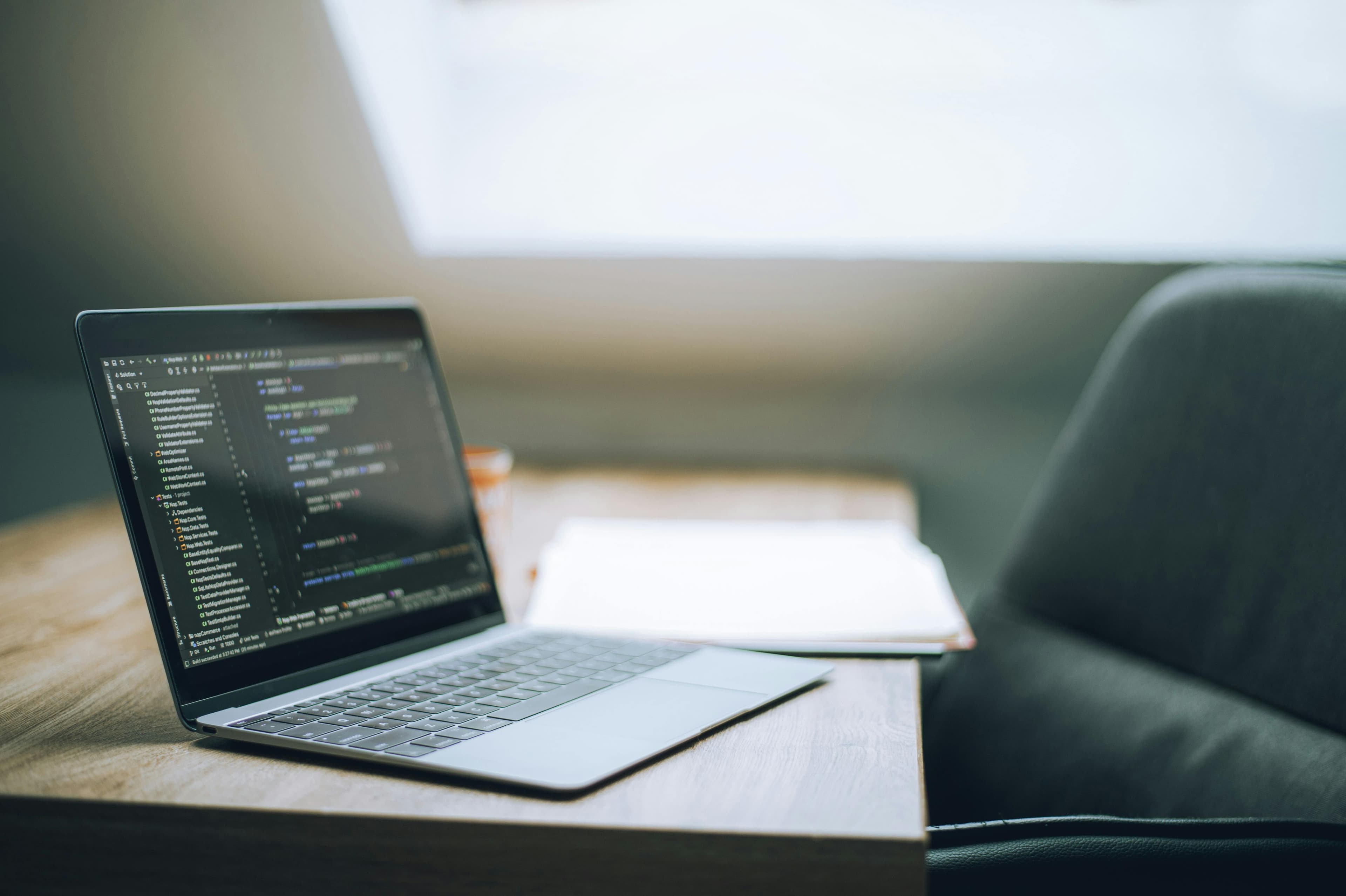 A laptop open on a desk in a soft modern office setting.