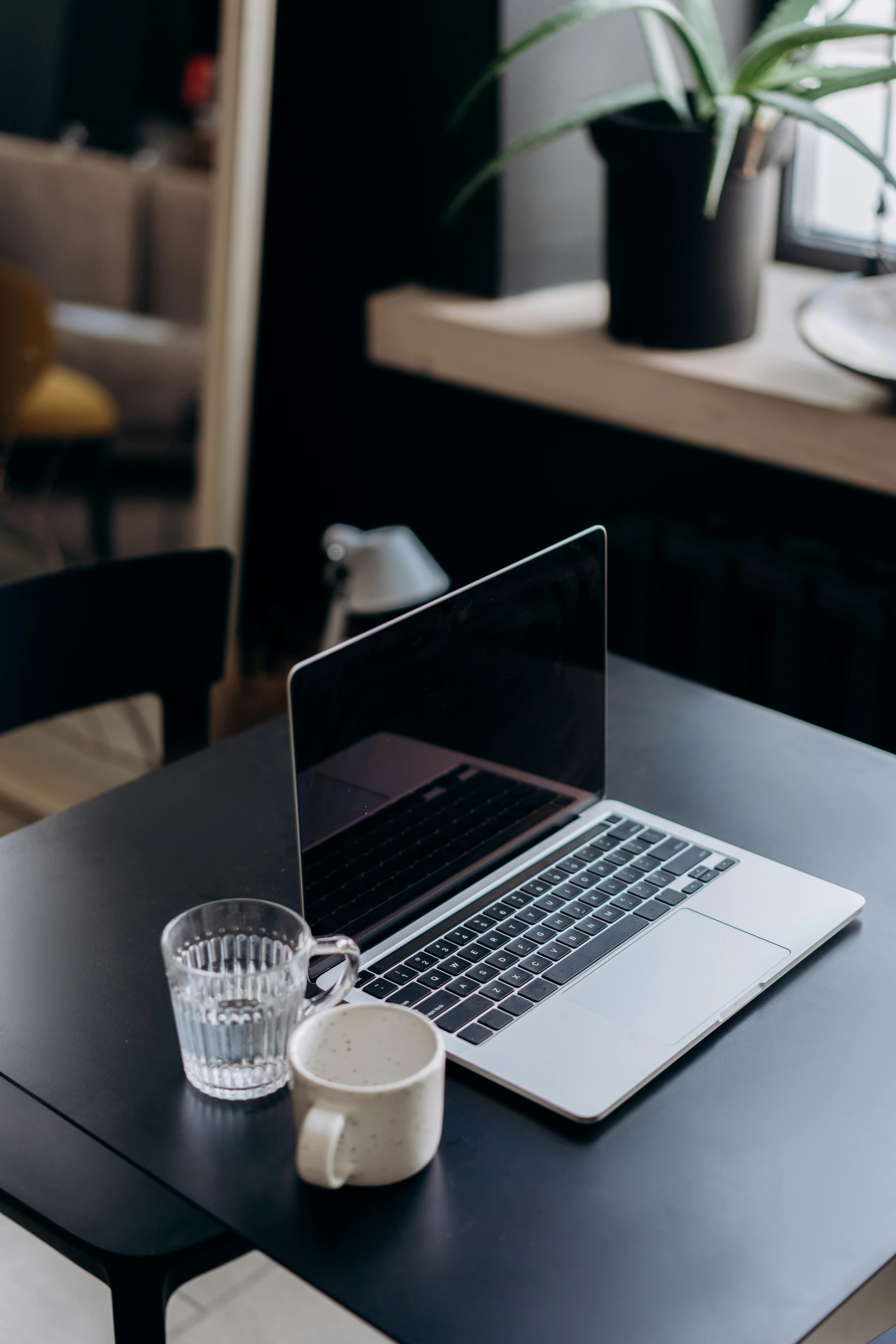 A laptop and coffee cup on a dark table in a stylish office.