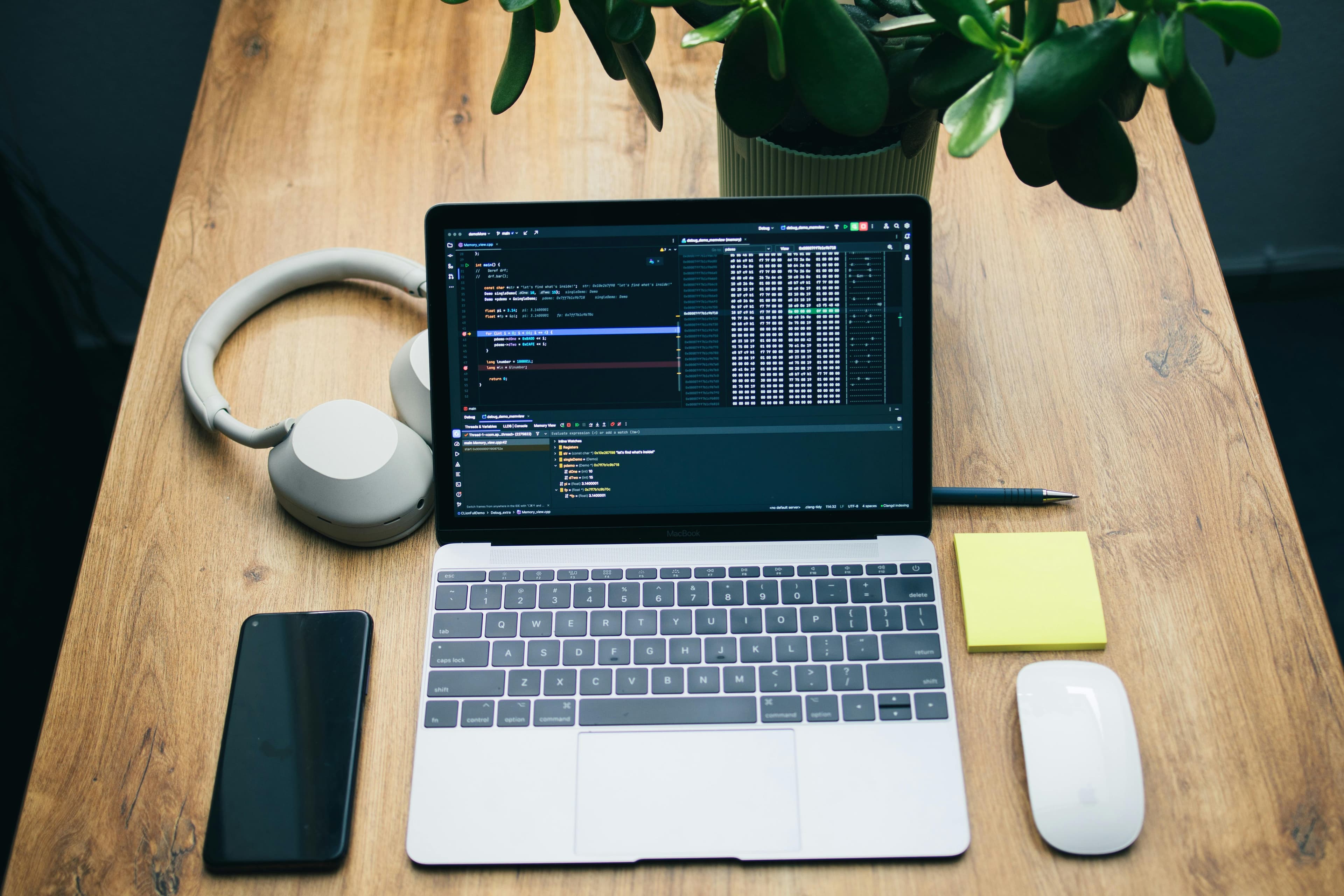 A top-down laptop workspace with headphones, phone, and notes.